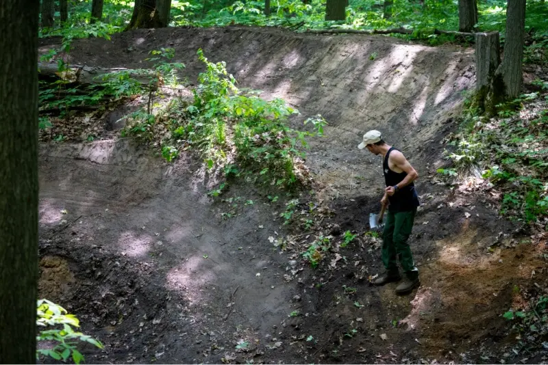 A man tending to trails with a rake