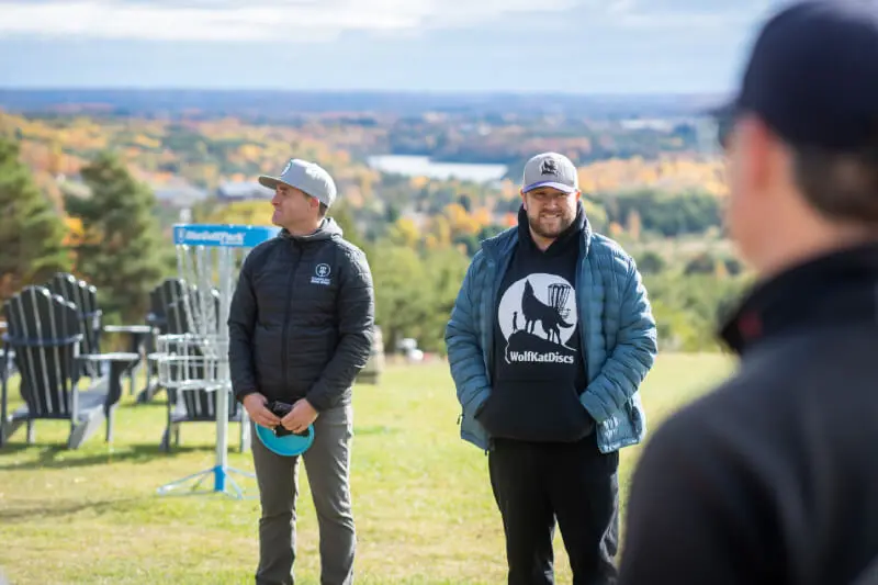 People standing by a frisbee golf hole.