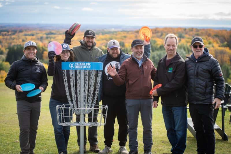 People standing around a Disc Golf hole