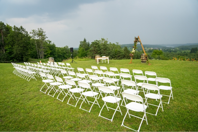 White wedding chairs on green grass set up for a ceremony